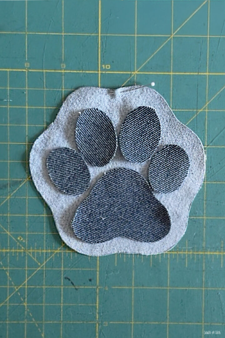 Denim base and paw print pieces cut for a fabric pattern weight